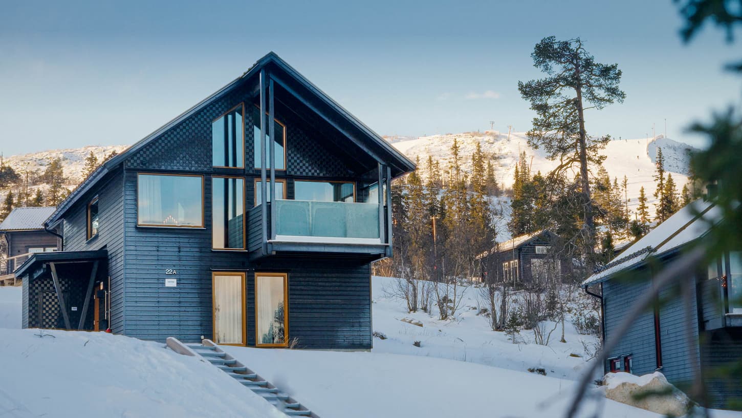 Fjällhus med solbelyst berg i bakgrunden